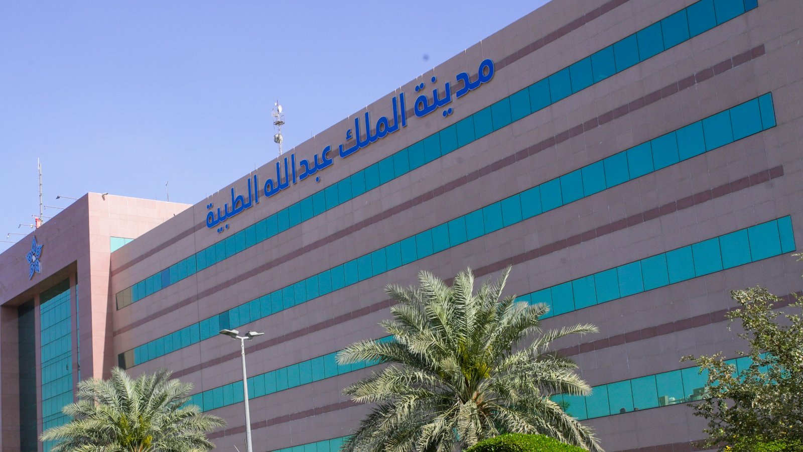 واجهة مبنى مدينة الملك عبدالله الطبية في مكة المكرمة تحيط به أشجار النخيل